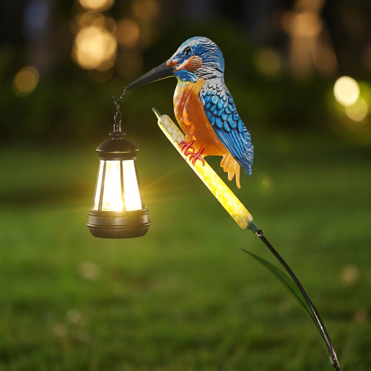 Bronze kingfisher solar lantern perched on a reed in a garden at night